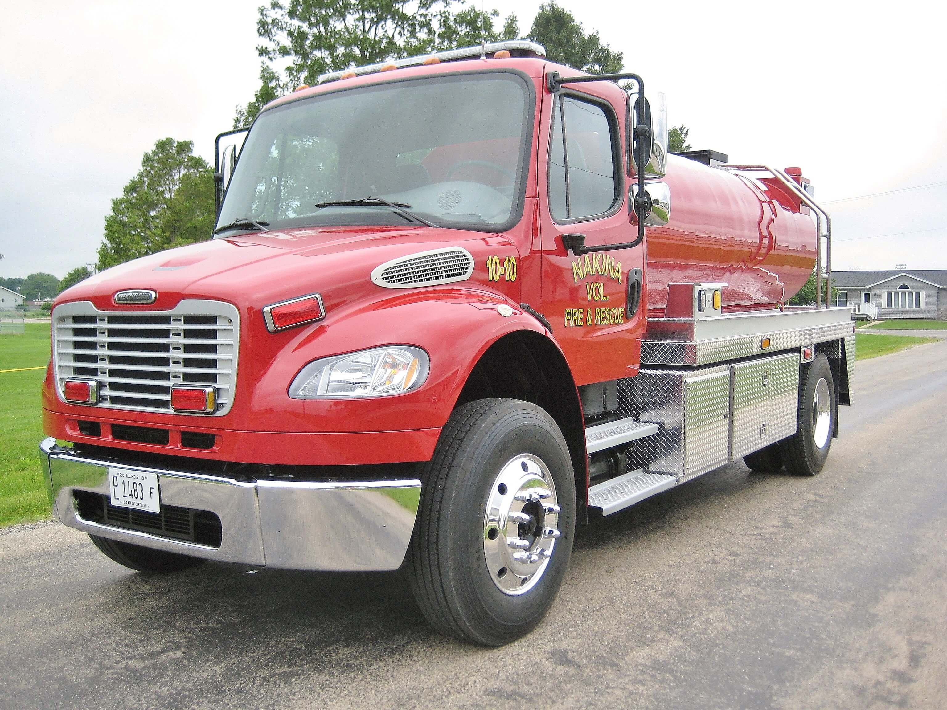 Full length view of an Osco Tank and Truck Sales Commander tanker truck with a red cab and red elliptical poly tank. Two silver stainless steel equipment boxes are mounted along the side of the truck.
